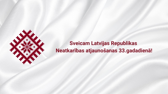 Balts galdauts un latviešu rakstsr ar auseklīti vidū karoga krāsā.