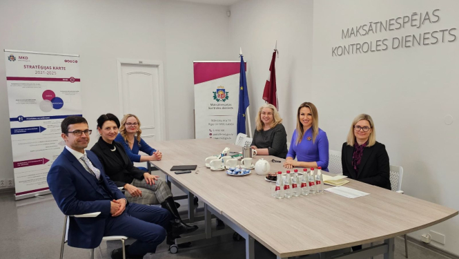 MKD un AA pārstāvji tikšanās reizē pie galda MKD telpās.