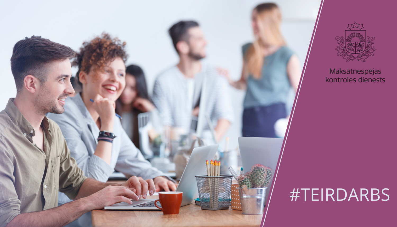 Priecīgi ļaudis sēž pie galda ar datoriem un sarunājas